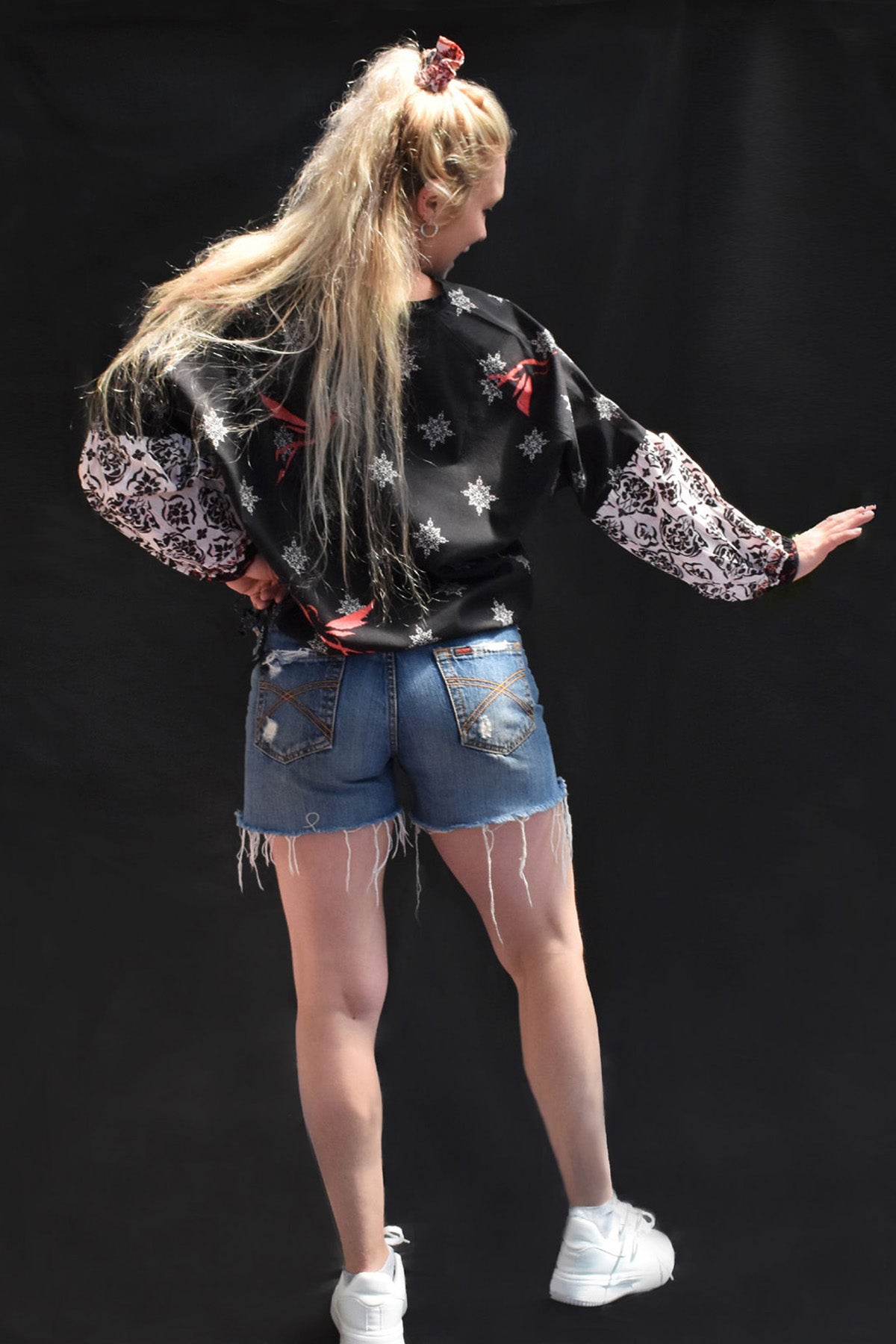 ORA PRINTED COTTON TOP - Back view-black printed v neck top with white printed motifs, sleeves are billowy in white with black print. Bright pink bird motif on front and back looks awesome. ties at the bottom and oversized fit.